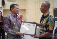 Foto Wakil Bupati Kutai Barat, H.Nanang Adriani Saat Menyerahkan Piagam Penghargaan Kepada Bahrin Selaku Kasi Pendidikan dan Kesehatan Kecamatan Penyinggahan Atas Prestasi Percepatan Penurunan Stunting.
