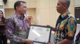 Foto Wakil Bupati Kutai Barat, H.Nanang Adriani Saat Menyerahkan Piagam Penghargaan Kepada Bahrin Selaku Kasi Pendidikan dan Kesehatan Kecamatan Penyinggahan Atas Prestasi Percepatan Penurunan Stunting.